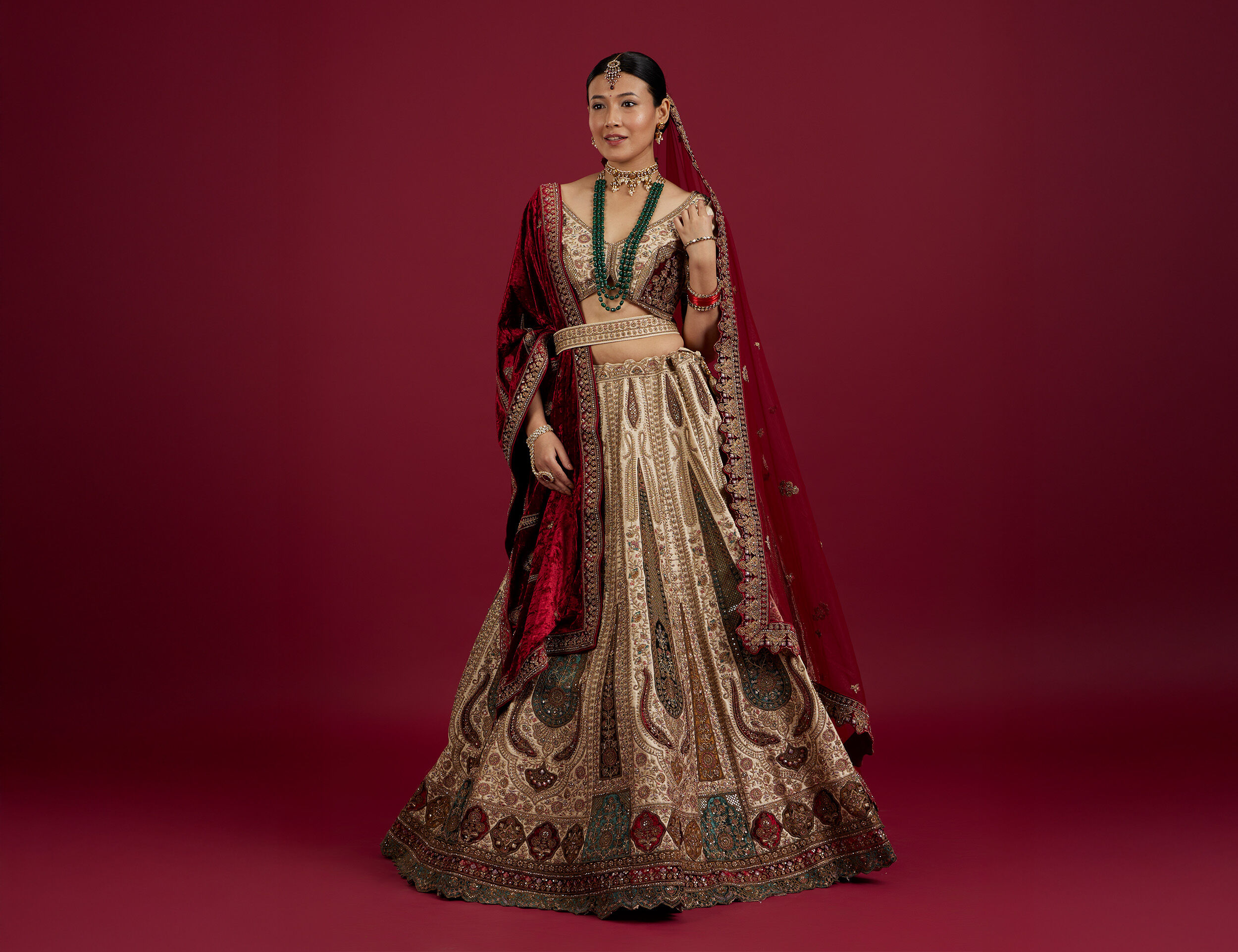 Bride wearing beautiful designed lehenga with red dupatta and blue pearl mala for wedding